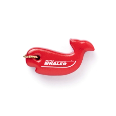 A red whale-shaped floating keychain with a metal ring. The Boston Whaler logo is printed in white on the whale’s body.