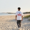 Man walking on beach wearing Boston Whaler Americana T-Shirt