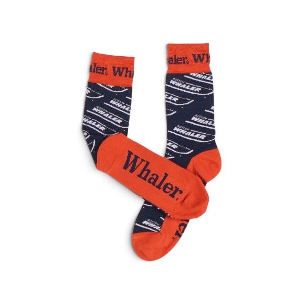Close-up view of navy and red Boston Whaler dress socks, showing the repeating Whaler text pattern and red toe and heel accents.